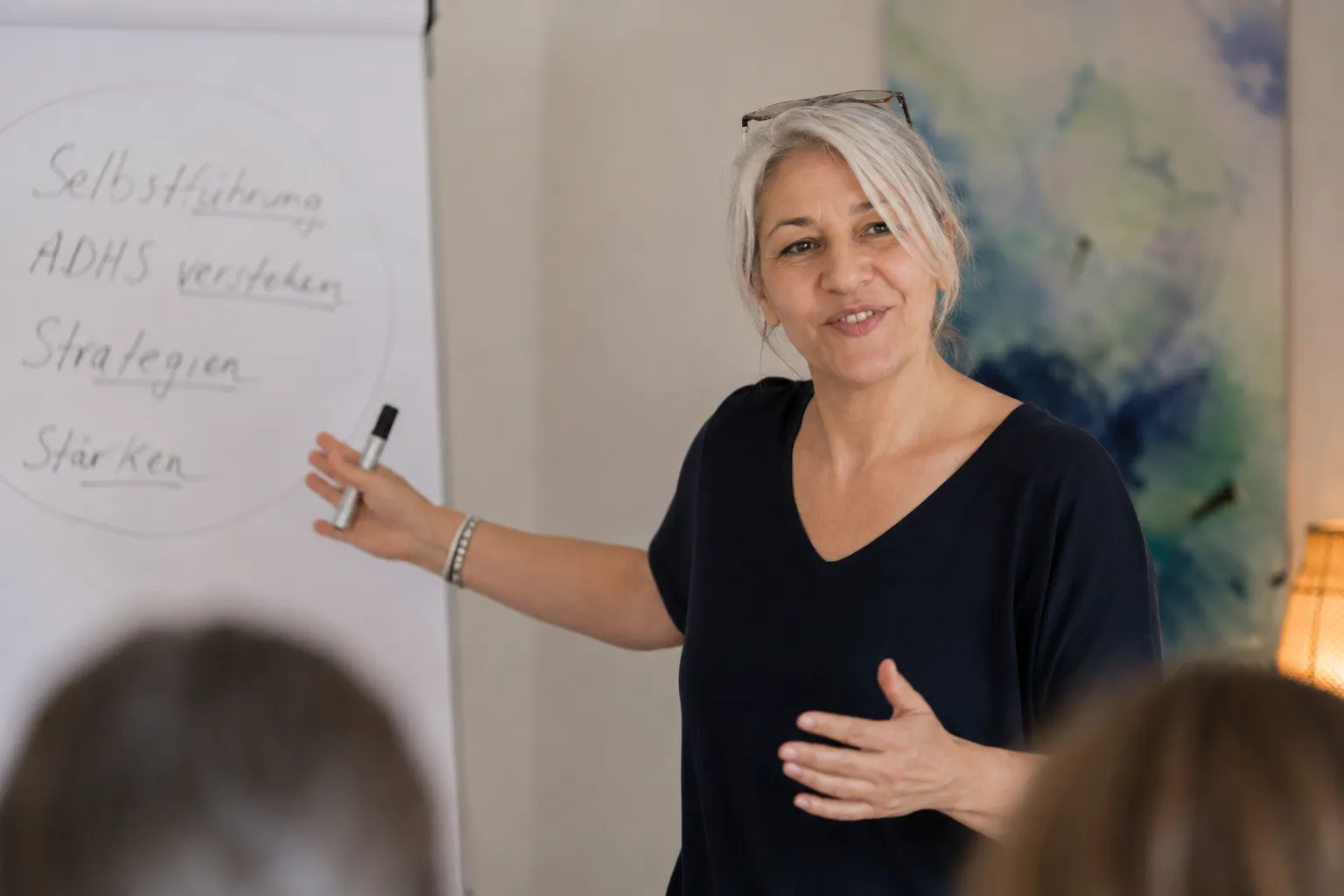 Funda Öcal während einer Schulung, im Hintergrund ein Flipchart mit den Stichpunkten Selbstführung, ADHS verstehen, Strategien, Stärken